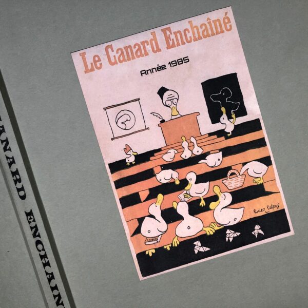 Couac ! | Année 1985 du Canard Enchaîné complète et brochée | Année complète et brochée 1985. Grand in folio 56.5 X 36.5 cm, feuilles parfaitement massicotées à ce format. 52 numéros originaux / 416 pages Les brochures sont réalisées par un artisan-brocheur, dans un très beau papier – Fedrigoni, dans la gamme Materica – 360 g, dont la fibre de coton procure un toucher incomparable, chargé en matière. Les couleurs crayeuses rappellent aussi les éléments : Terra Rossa utilisée pour les années paires, Verdigris, pour les années impaires. Ce papier est teinté dans la masse et fabriqué avec 40% de fibres CTMP, 25% de fibres vierges, 25% de fibres recyclées et 10% de fibres de coton. - Sans acide ECF – Ph neutre – certifié FSC - Au centre de la couverture est enchâssée la reproduction fidèle du dessin de Lucien Laforge - un des tous premiers dessinateurs au Canard Enchainé - qui illustrait la pochette offerte aux abonnés de la première heure, soit ceux de 1916... la quatrième de couverture reprend le cabochon de cette même pochette d'origine, figurant un poilu lisant le "Canard". Le dos est carré et collé, les plats sont souples avec rabats intérieurs. Tous les numéros sont solidaires et ordonnés suivant l'ordre chronologique, ils peuvent comporter quelques jaunissements au droit des anciennes pliures ou petites restaurations. La photo présentée correspond à celle de l'exemplaire original en vente, prise en lumière naturelle (ce n'est pas une photo générique). | IMG 8288