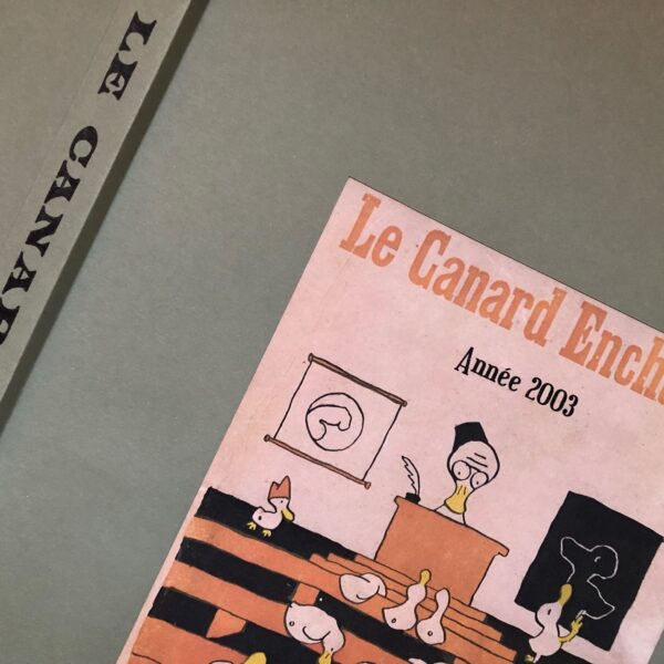 Couac ! | Année 2003 du Canard Enchaîné complète et brochée | Année complète et brochée 2003. Grand in folio 57 X 35.5 cm, feuilles parfaitement massicotées à ce format. 52 numéros originaux / 416 pages. Les brochures sont réalisées par un artisan-brocheur, dans un très beau papier – Fedrigoni, dans la gamme Materica – 360 g, dont la fibre de coton procure un toucher incomparable, chargé en matière. Les couleurs crayeuses rappellent aussi les éléments : Terra Rossa utilisée pour les années paires, Verdigris, pour les années impaires. Ce papier est teinté dans la masse et fabriqué avec 40% de fibres CTMP, 25% de fibres vierges, 25% de fibres recyclées et 10% de fibres de coton. - Sans acide ECF – Ph neutre – certifié FSC - Au centre de la couverture est enchâssée la reproduction fidèle du dessin de Lucien Laforge - un des tous premiers dessinateurs au Canard Enchainé - qui illustrait la pochette offerte aux abonnés de la première heure, soit ceux de 1916... la quatrième de couverture reprend le cabochon de cette même pochette d'origine, figurant un poilu lisant le "Canard". Le dos est carré et collé, les plats sont souples avec rabats intérieurs. Tous les numéros sont solidaires et ordonnés suivant l'ordre chronologique, ils peuvent comporter quelques jaunissements au droit des anciennes pliures ou petites restaurations. La photo présentée correspond à celle de l'exemplaire original en vente, prise en lumière naturelle (ce n'est pas une photo générique).     | IMG 8318